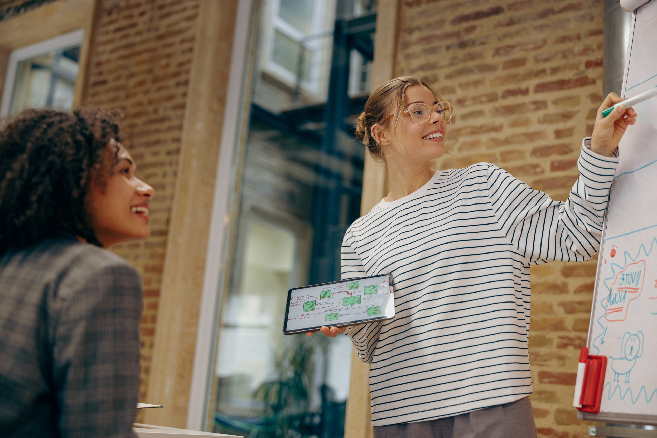 Smiling female employee giving a presentation to his colleague standing in front of a flipchart